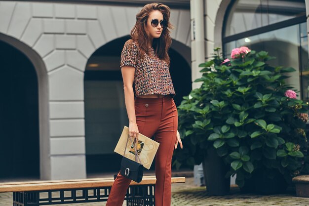 Belle brune à la mode portant des vêtements à la mode et des lunettes de soleil.