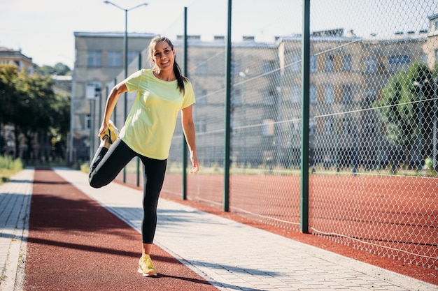 Belle brune qui s'étend des jambes au stade moderne