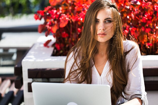 Belle brune travaille avec un ordinateur portable à l&#39;extérieur