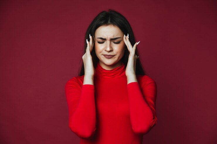 Photo gratuit belle brunette caucasienne fille vêtue d'un pull rouge avec des maux de tête douloureux