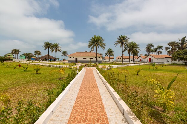 Belle chaussée et les maisons entourées de champs herbeux capturés en Gambie, Afrique