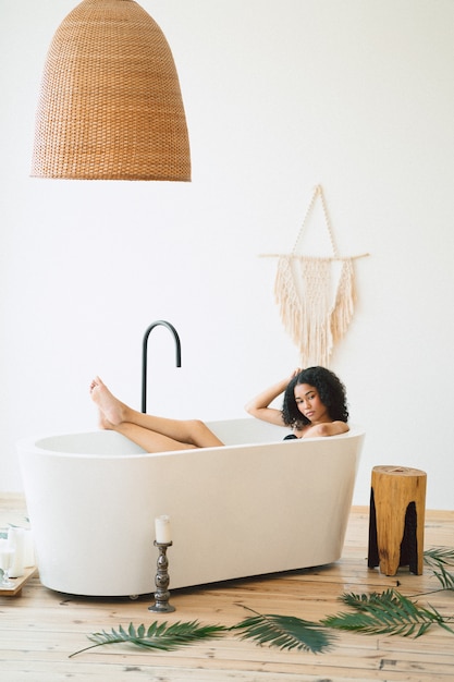 Photo gratuite belle dame ayant un bain de lait et pensant dans une pièce vide.