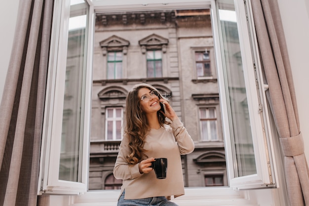 Belle dame blanche heureuse se détendre le matin avec une tasse de boisson chaude