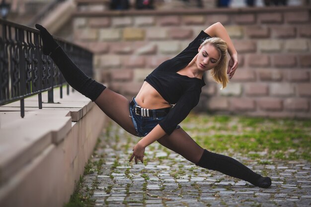 Belle danseuse de ballet ou danse acrobatique à l'extérieur dans la rue