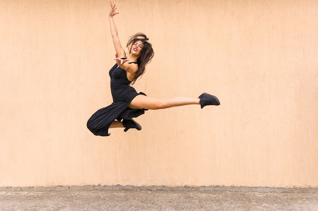 Photo gratuite belle danseuse de tango sautant en l'air contre la toile de fond de mur