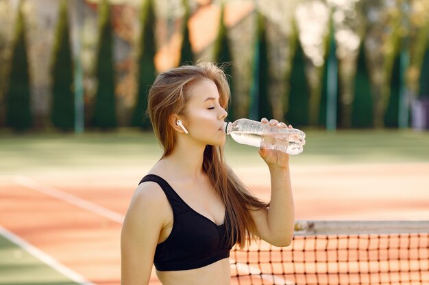 Belle et élégante fille sur le court de tennis