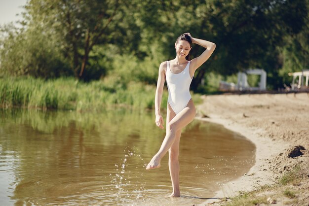 Belle et élégante fille sur une plage près du lac