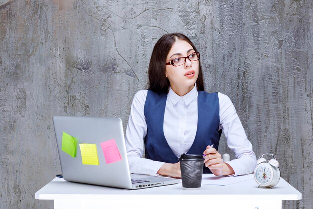 Belle employée de bureau à lunettes travaillant derrière l'ordinateur portable au bureau. Photo de haute qualité