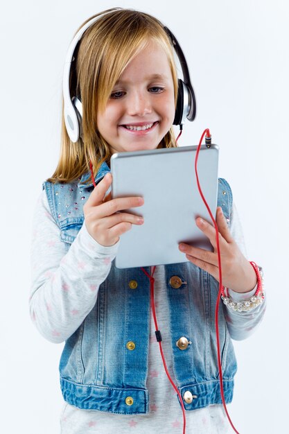 Belle enfant écoutant de la musique avec une tablette numérique.