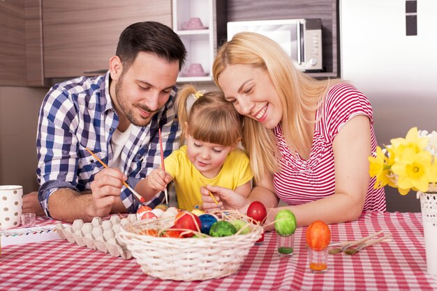 Belle famille peignant les oeufs de Pâques avec leur enfant