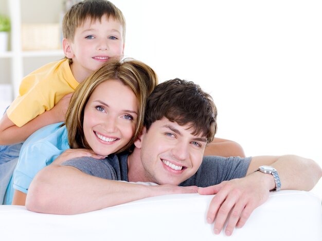 Belle famille souriante heureuse de trois personnes avec jeune fils - à l'intérieur