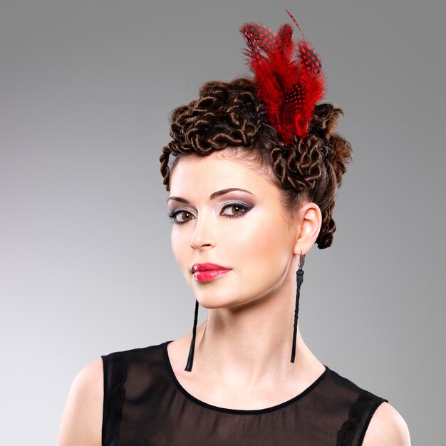 Photo gratuite belle femme adulte avec une coiffure de mode avec une plume rouge dans les cheveux