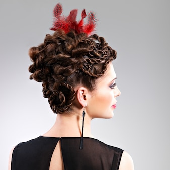 Belle femme adulte avec une coiffure de mode avec une plume rouge dans les cheveux