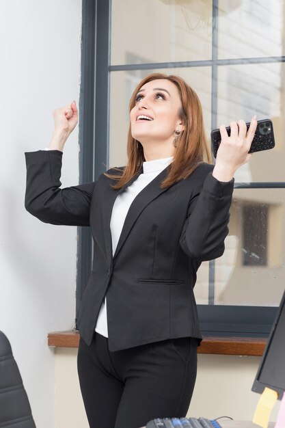 Belle femme d'affaires debout au bureau et se sentant heureuse