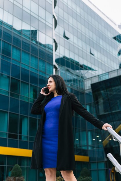 Belle femme d&#39;affaires parlant sur smartphone devant l&#39;immeuble