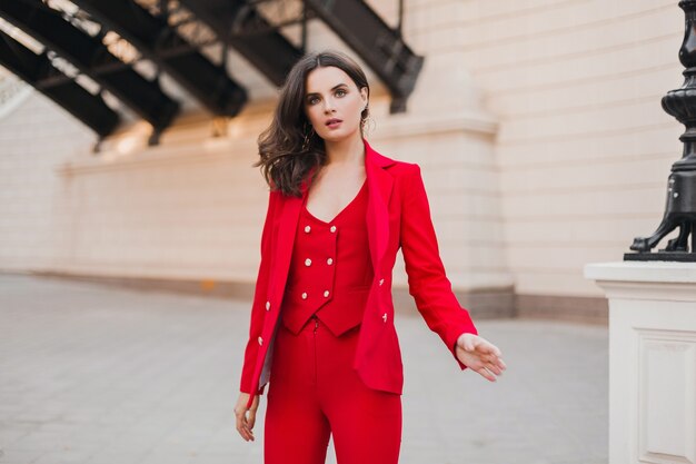 Belle femme d'affaires riche sexy en costume rouge marchant dans la rue de la ville, tendance de la mode printemps été