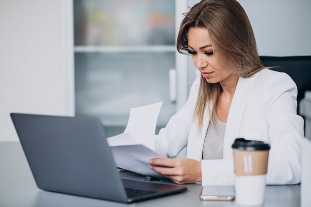 Belle femme d'affaires travaillant sur ordinateur au bureau et boire du café