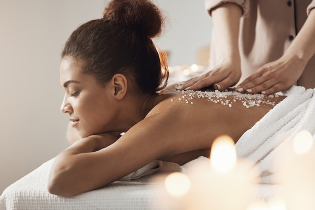 Belle femme africaine au repos, profitant d'un massage santé spa avec du sel marin.