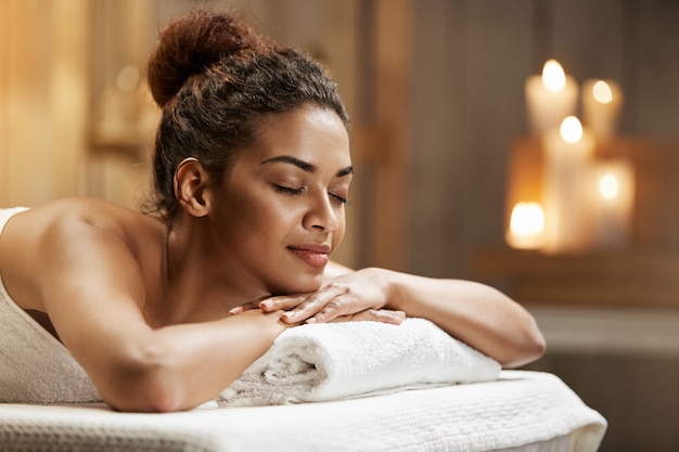 Belle femme africaine au repos relaxante dans une station thermale avec les yeux fermés.