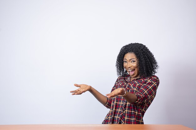 Belle femme africaine faisant des gestes à l'espace vide de son côté avec excitation