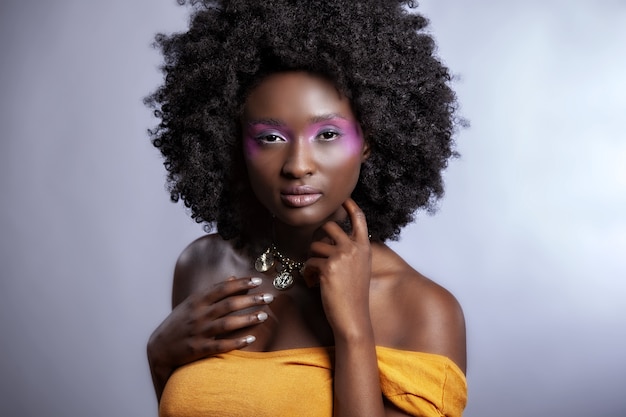 Belle femme africaine avec de grands Afro bouclés et des fleurs dans ses cheveux