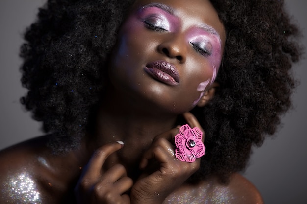 Belle femme africaine avec de gros Afro bouclés et des fleurs dans ses cheveux