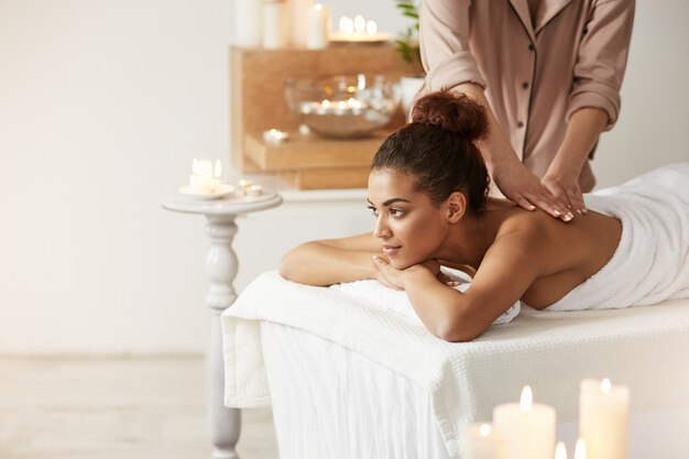 Belle femme africaine souriante appréciant le massage dans la station thermale.