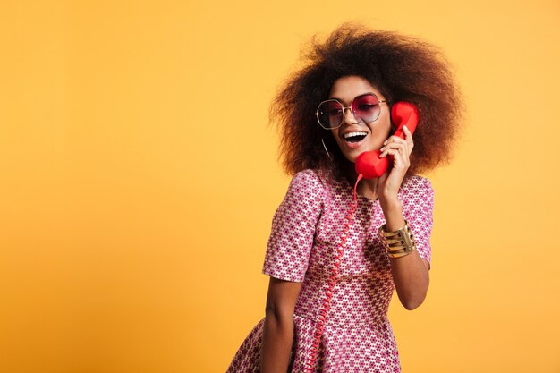 Belle femme africaine souriante en robe posant avec téléphone rétro