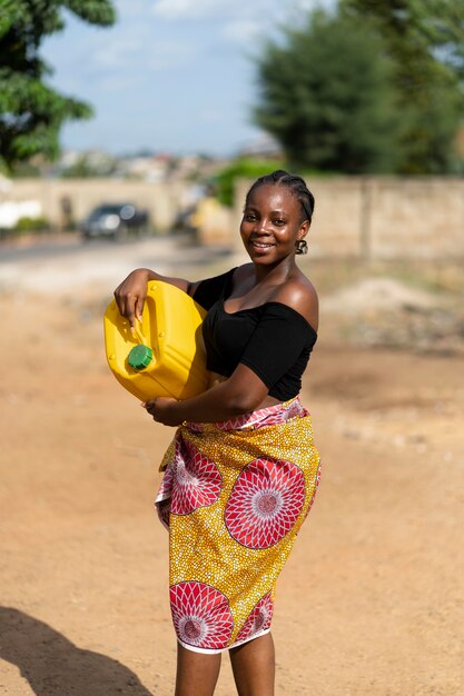 Belle femme africaine tenant un récipient d'eau jaune