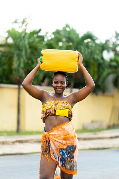 Belle femme africaine tenant un récipient d'eau