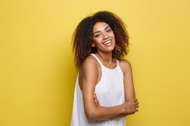 Belle femme afro-américaine attrayante avec des lunettes à la mode posant sur un fond de studio jaune. Espace de copie.