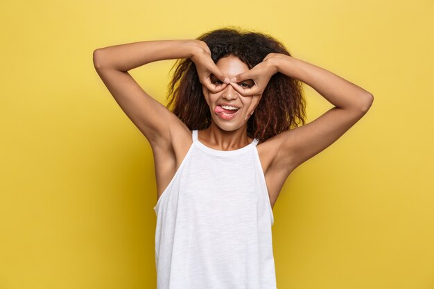 Belle femme afro-américaine attrayante avec des lunettes à la mode posant sur un fond de studio jaune. Espace de copie.