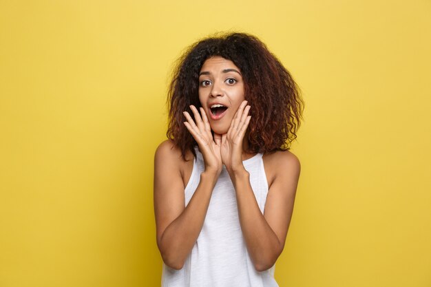 Belle femme afro-américaine attrayante avec des lunettes à la mode posant sur un fond de studio jaune. Espace de copie.