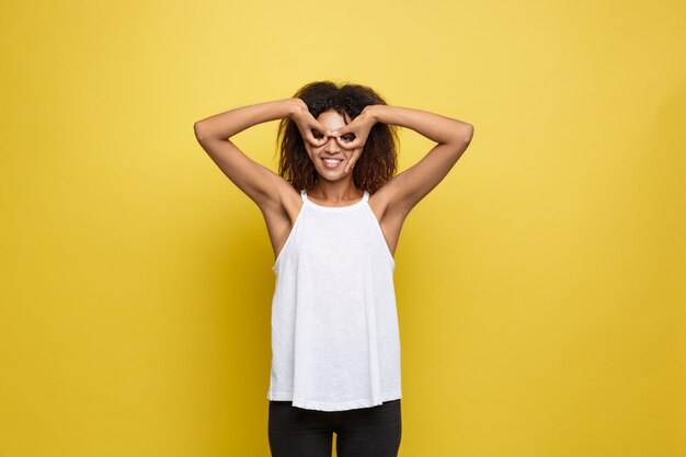 Belle femme afro-américaine attrayante posant jouer avec ses cheveux bouclés d&#39;afro. Fond d&#39;écran jaune. Espace de copie.