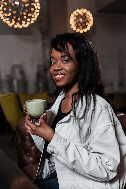 Belle femme afro-américaine tenant un café