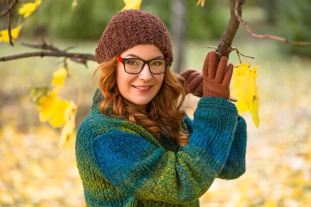 Belle femme d'âge moyen dans des verres souriant pour la caméra et tenant une branche d'arbre