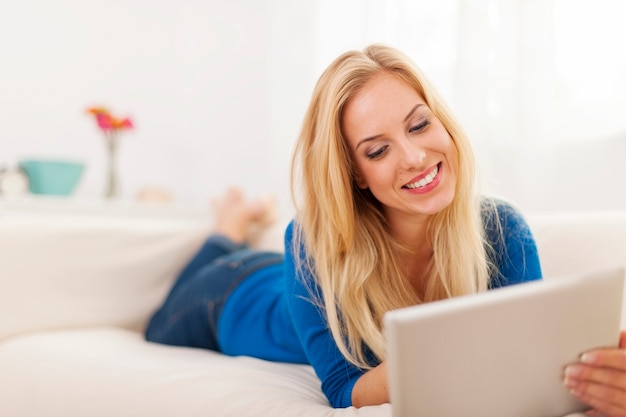 Belle femme allongée sur le canapé et à l'aide de tablette numérique