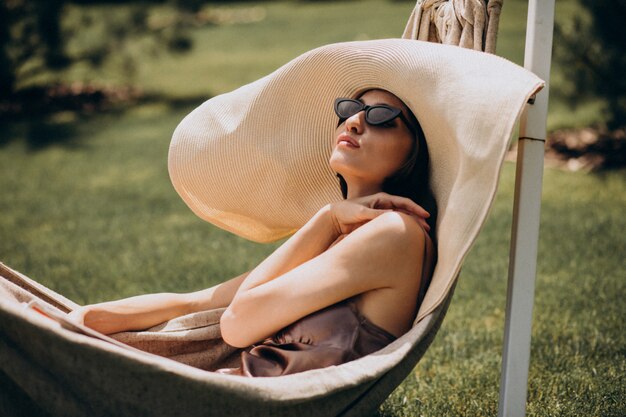 Belle femme allongée dans un hamac portant un gros chapeau de soleil