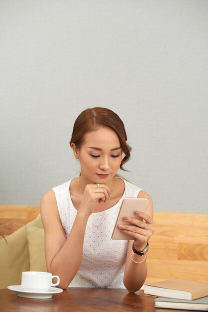 Belle femme asiatique à l'aide de smartphone à la maison