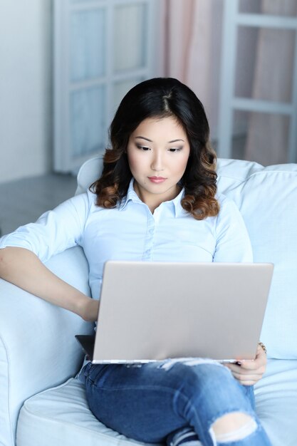 Belle femme asiatique à la maison avec ordinateur portable