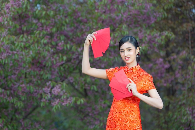 Photo gratuite belle femme asiatique montre quelque chose et prend des enveloppes rouges au nouvel an chinois