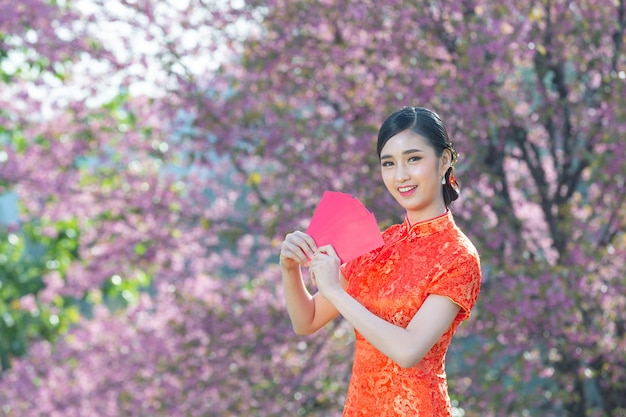 Photo gratuite belle femme asiatique montre quelque chose et prend des enveloppes rouges au nouvel an chinois