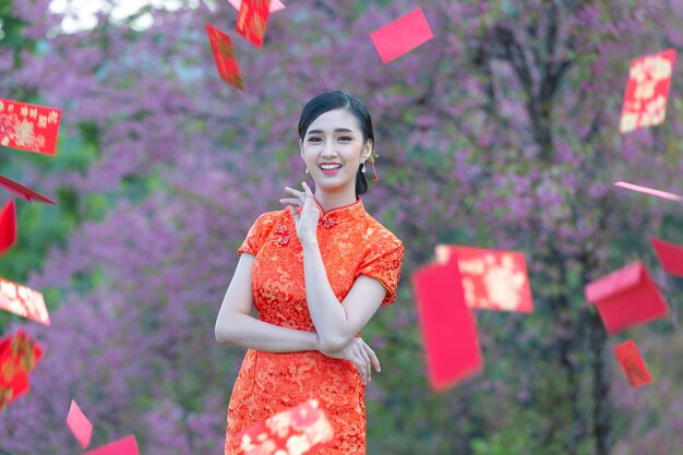 Belle femme asiatique montre quelque chose et prend des enveloppes rouges au nouvel an chinois