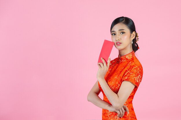 Belle femme asiatique montre quelque chose et prend des enveloppes rouges au nouvel an chinois