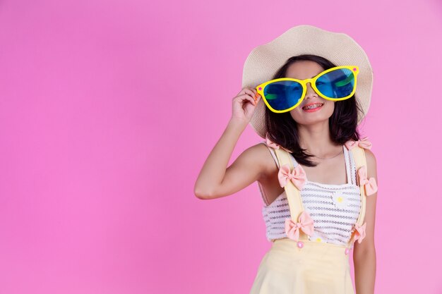 Une belle femme asiatique portant un chapeau et de grandes lunettes avec une rose.