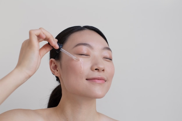 Belle femme asiatique posant avec de la crème pour le visage