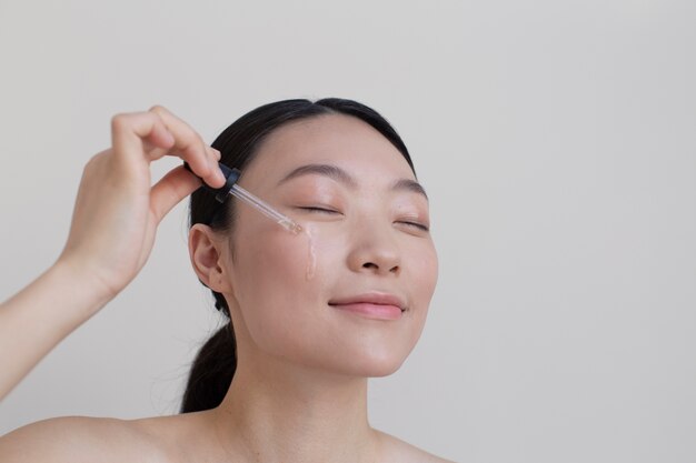 Belle femme asiatique posant avec de la crème pour le visage