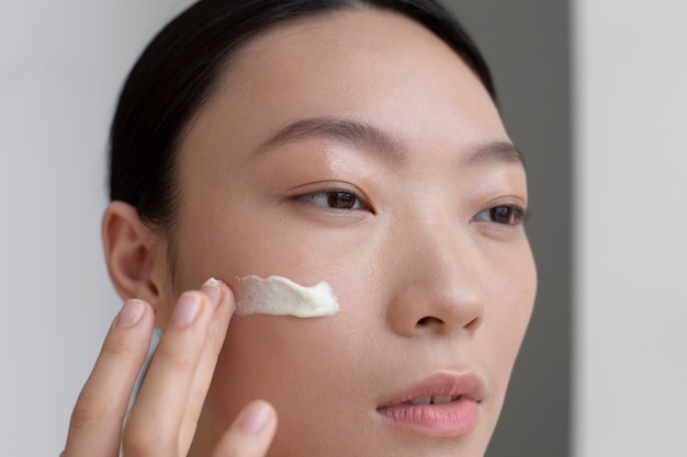 Belle femme asiatique posant avec de la crème pour le visage