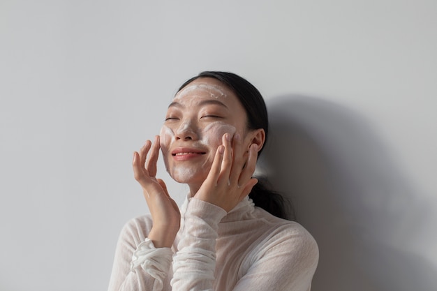 Belle femme asiatique posant avec de la crème pour le visage