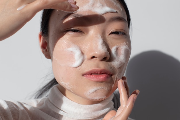 Belle femme asiatique posant avec de la crème pour le visage